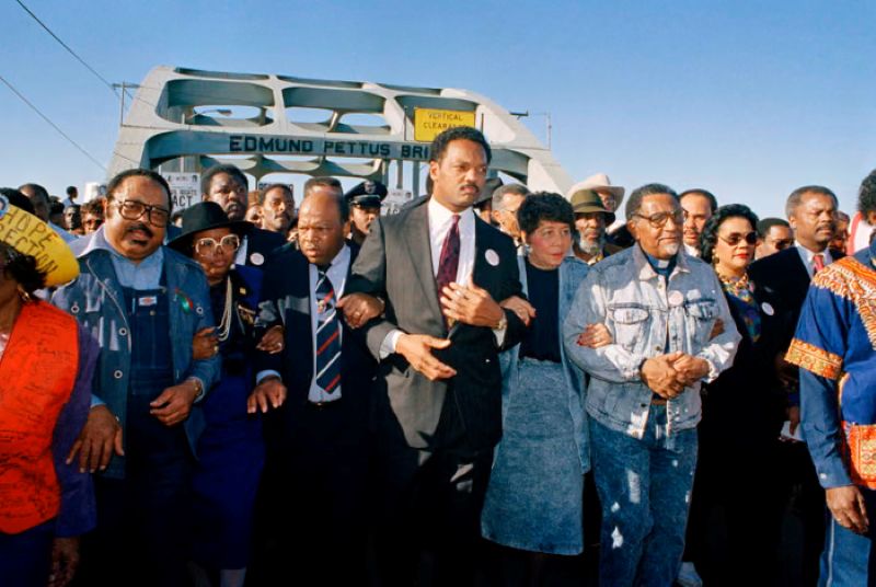 Tokoh-tokoh hak sipil memimpin para peserta pawai melintasi Jembatan Edmund Pettus selama rekonstruksi pawai Selma ke Montgomery tahun 1965 di Selma, Alabama, pada 4 Maret 1990.