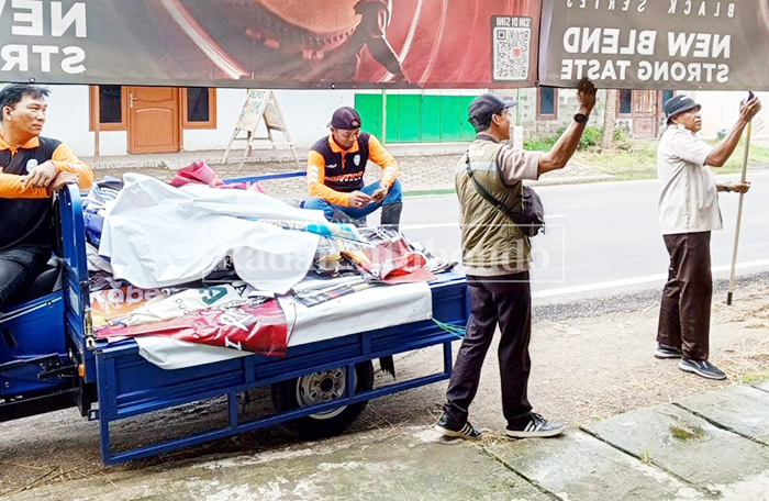 TERTIB PAJAK: Anggota Satpol PP Situbondo menurunkan reklame ilegal di pinggir Jalan Raya Kecamatan Panji, Selasa (24/2). 