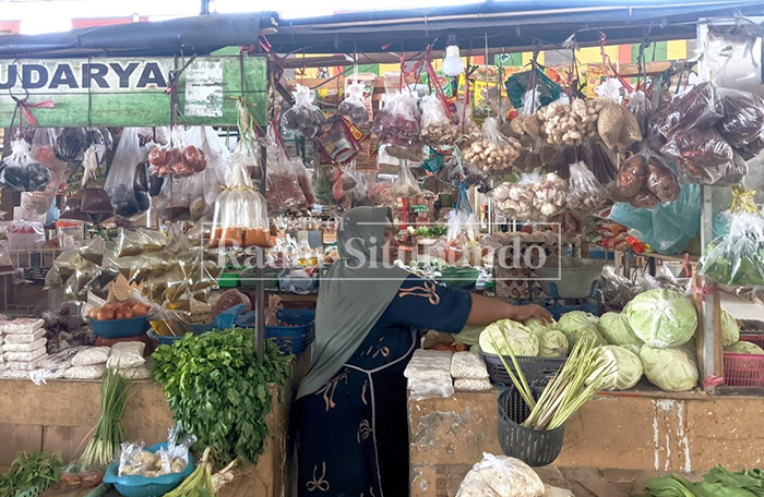 MELAYANI: Pedagang mengambil bahan pokok yang akan dibeli konsumen di Pasar Tradisional Mimbaan Baru, Kecamatan Panji, belum lama ini.  