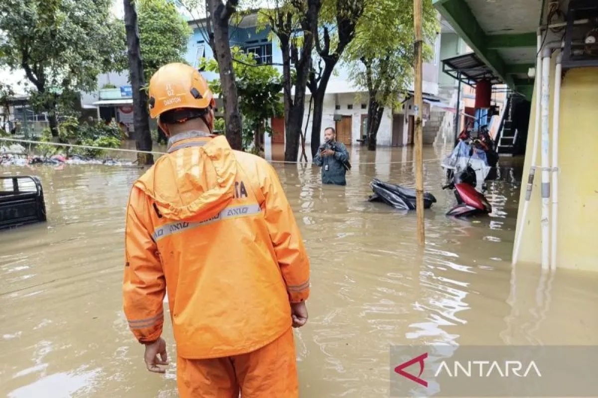 Seorang petugas BPBD DKI Jakarta saat memantau kondisi banjir di Jakarta, Minggu (8/3/2026).