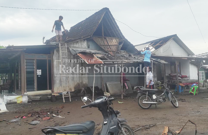 Sejumlah warga menaiki atap rumah untuk memasang kembali asbes yang rusak akibat diterjang angin puting beliung di Dusun Corasale, Desa Seletreng, Kecamatan Kapongan, Minggu (8/3). 
