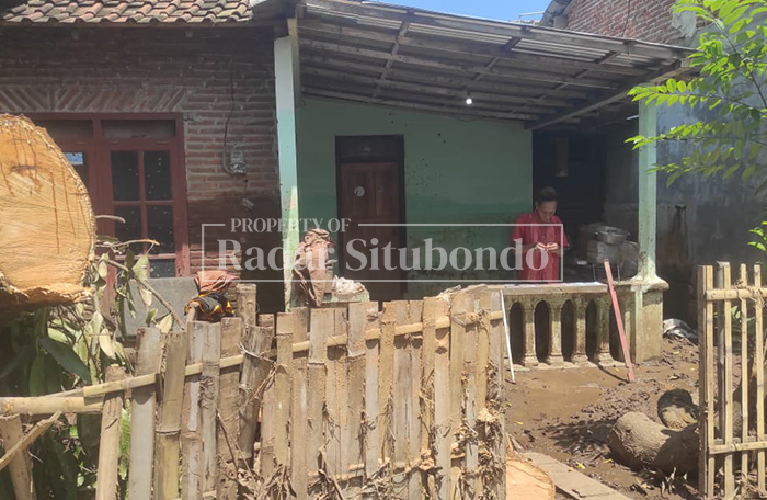 HANYA BISA PASRAH: Salah satu warga berdiam diri di depan rumahnya yang terdampak banjir di Desa Kalianget, Kecamatan Banyuglugur, Jumat (13/3).  