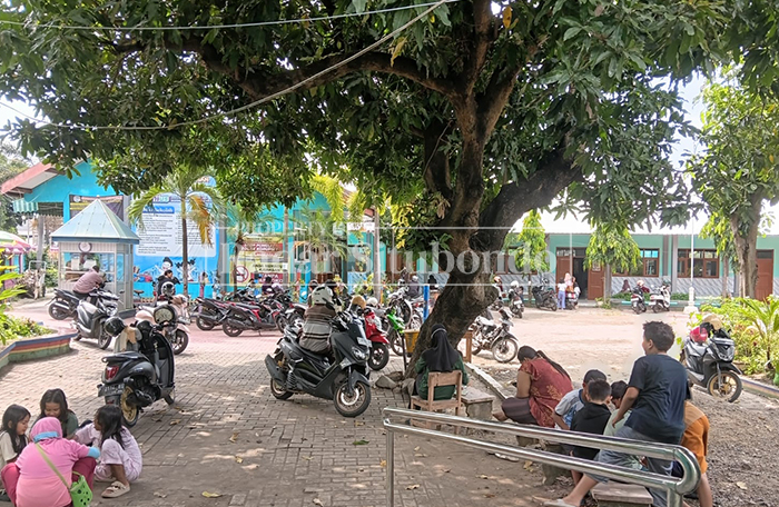 MENUNGGU: Wali murid menunggu pengiriman Makan Bergizi Gratis (MBG) di salah satu sekolah dari Satuan Pelayanan Pemenuhan Gizi (SPPG) Mimbaan 003, Senin (16/3). 