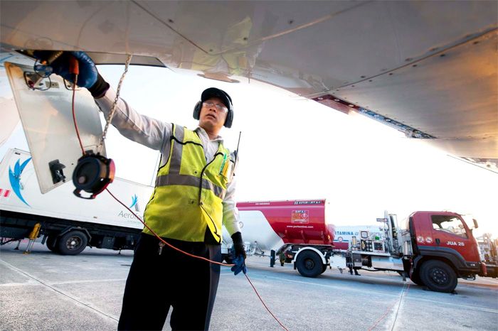 Ilustrasi petugas tengah mengisi avtur sebuah pesawat.