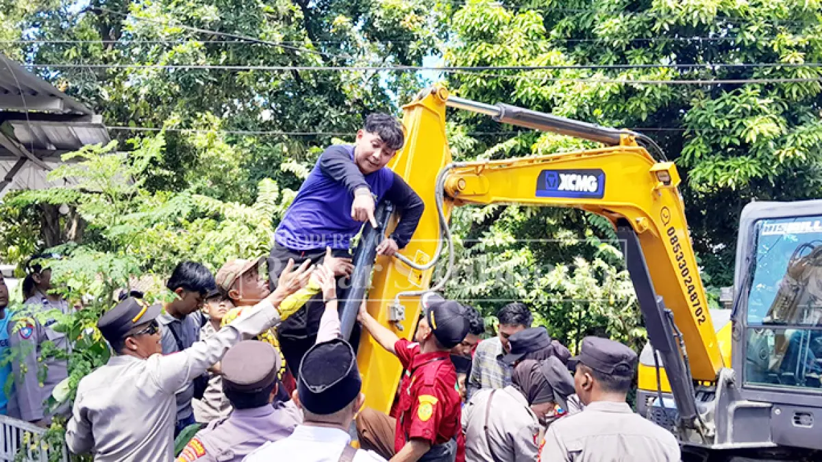 PERTAHANKAN HAK MILI: Hairul pemilik rumah di Desa Juglangan, Kecamatan Panji naik ke ekskavator untuk menggagalkan eksekusi tanah yang dilakukan juru sita Pengadilan Negeri (PN) Situbondo, Rabu (22/4). (HUMAIDI/JPRS)
