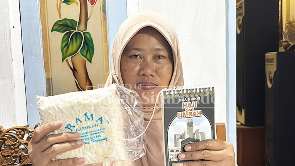 BERAKTIVITAS: Seini, 46, penjual tempe asal  Kecamatan Asembagus, menun­jukkan kartu pemberangkatan haji, Senin (4/5). (HUMAIDI/JPRS)
