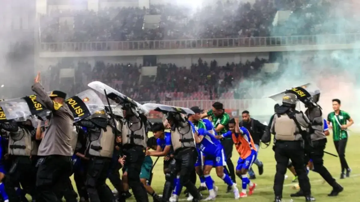 Aparat keamanan mengawal pemain Adhyaksa FC keluar lapangan Stadion Lukas Enembe, Jayapura, Jumat (8/5/2026), usai kericuhan pecah setelah Persipura Jayapura gagal promosi ke Super League musim depan. (ANTARA)