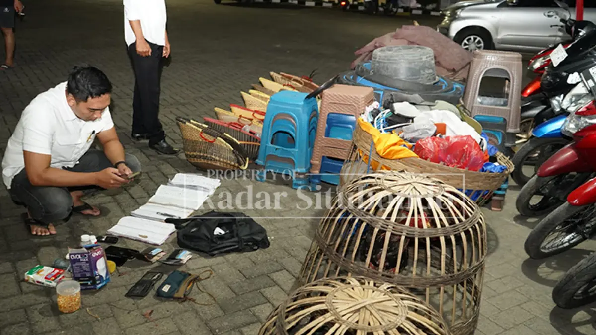 BARANG BUKTI: Anggota Polres Situbondo menghitung barang bukti sabung ayam di halaman depan Mapolres Situbondo, Sabtu malam (9/5). (HUMAIDI/JPRS)
