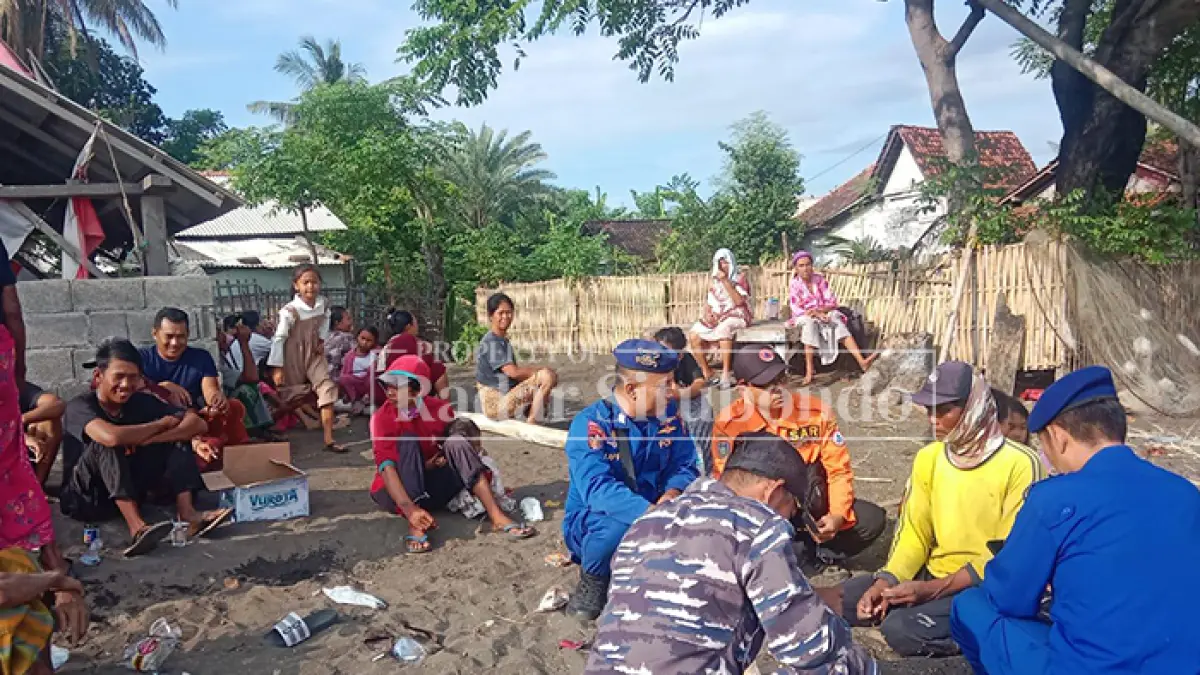 KAUS KUNING: Kusnadi, 38, bercengkrama dengan anggota Satpolairud Polres Situbondo di pinggir laut Desa/Kecamatan Jangkar, Selasa (26/5). (HUMAIDI/JPRS)
