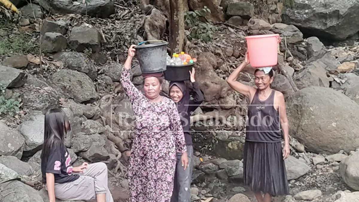 DEMI KEBUTUHAN: Seorang warga membawa air melintasi medan naik-turun perbukitan di Desa Gunung Putri, Kecamatan Suboh, Senin (22/6). (Ahmad Rifa