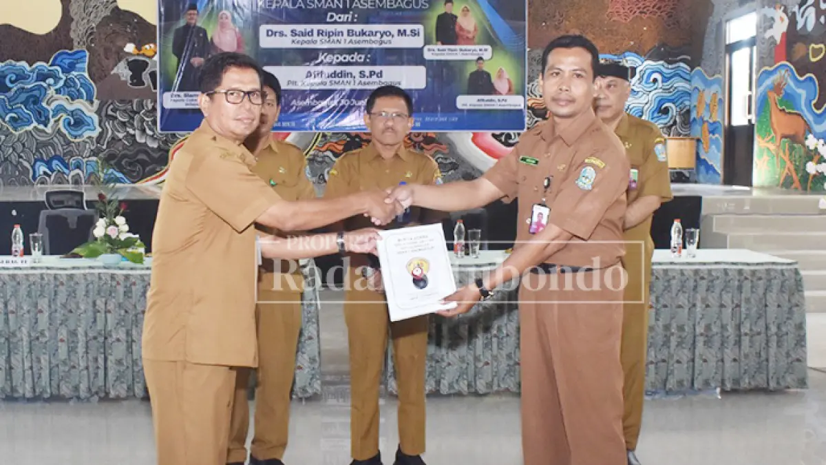 SERAH TERIMA: Kepala SMAN 1 Asembagus, Drs. Said Ripin Bukaryo (kiri), menyerahkan berita acara serah terima jabatan kepada Pelaksana Tugas (Plt) Kepala SMAN 1 Asembagus, Afifudin, S.Pd., usai memasuki masa purna tugas per 30 Juni 2026, Selasa (30/6). (Ahmad Rifa