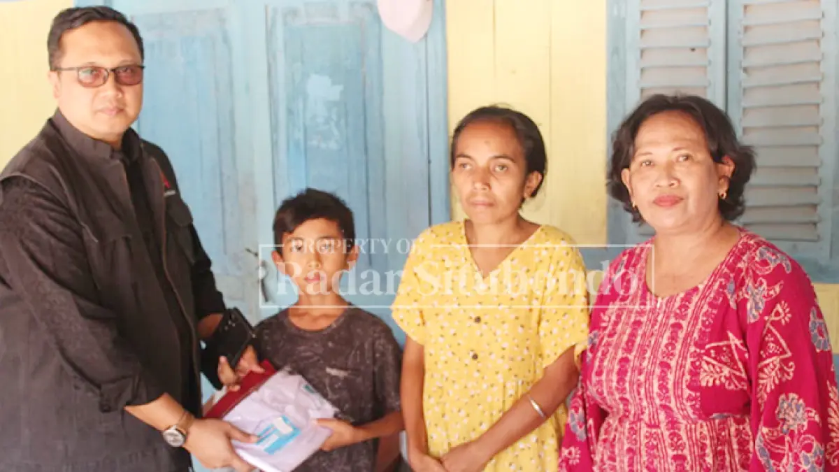 WUJUD KEPEDULIAN: Ketua DPC PDI Perjuangan, Andi Handoko menyerahkan bantuan seragam kepada siswa kurang mampu di Situbondo, Minggu (12/7). (Ahmad Rifa