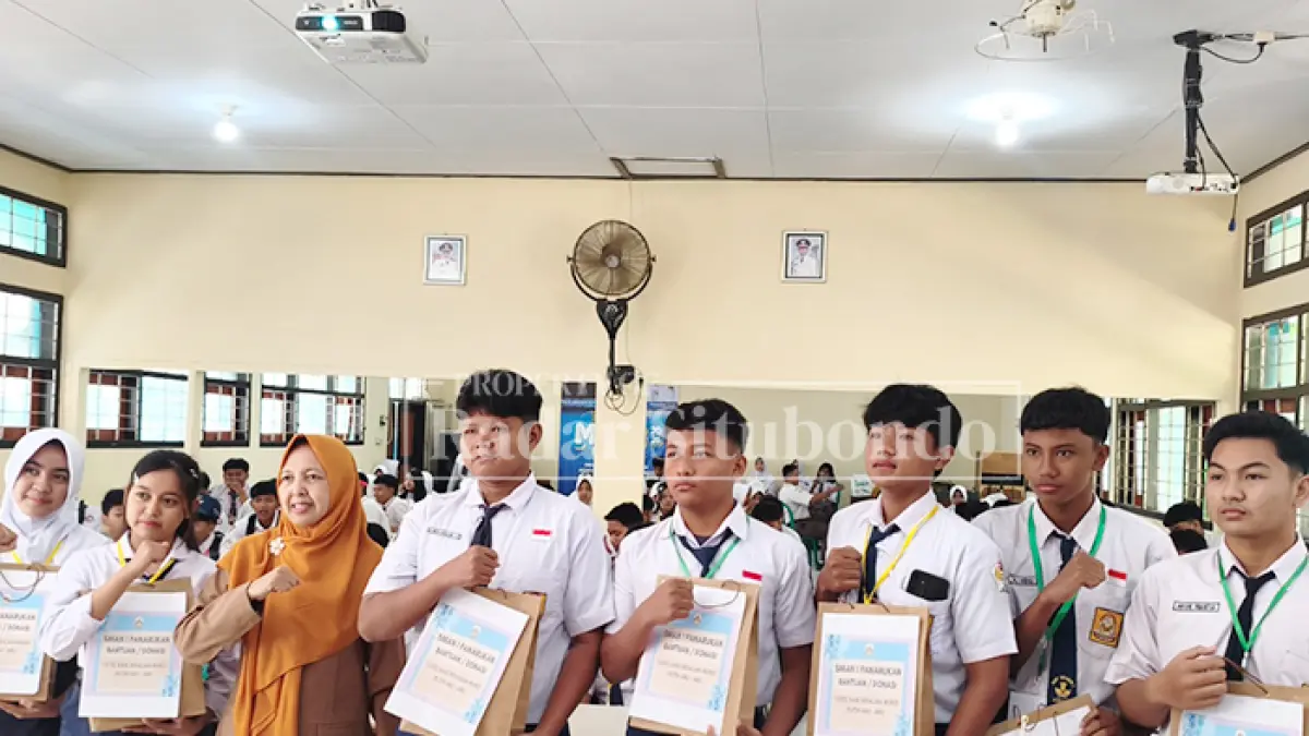 FOTO BERSAMA: Kepala SMAN 1 Panarukan, Nunung Pujiastutik, M.Pd., (tengah) menyerahkan seragam sekolah gratis kepada murid baru saat kegiatan Masa Pengenalan Lingkungan Sekolah (MPLS) Ramah di SMAN 1 Panarukan, Kabupaten Situbondo, Jumat (17/7). (Ahmad Rifa