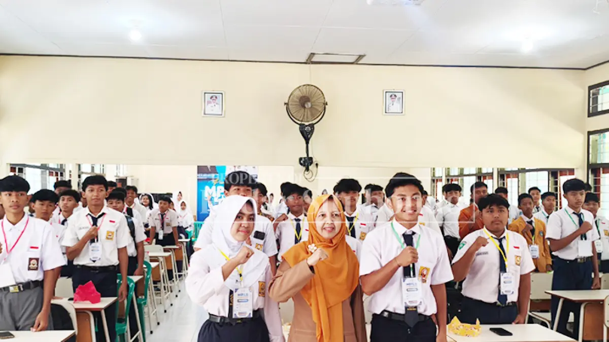 FOTO BERSAMA: Kepala SMAN 1 Panarukan, Nunung Pujiastutik, M.Pd., (tengah) menyerahkan seragam sekolah gratis kepada murid baru saat kegiatan Masa Pengenalan Lingkungan Sekolah (MPLS) Ramah di SMAN 1 Panarukan, Kabupaten Situbondo, Jumat (17/7). (Ahmad Rifa