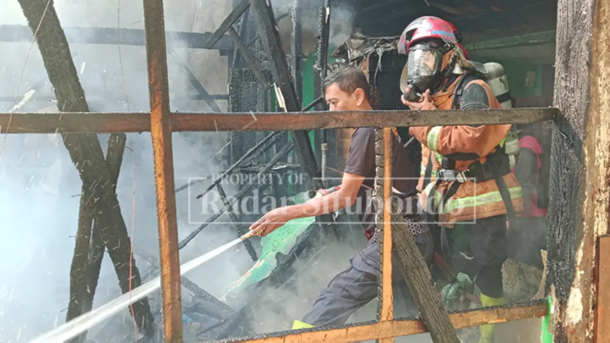 RUSAK BERAT: Anggota pemadam kebakaran (Damkar) Situbondo memadamkan api di rumah Rustami Arifin, 46, di Kelurahan Mimbaan, Kecamatan Panji, Selasa (28/7). (HUMAIDI/JPRS)
