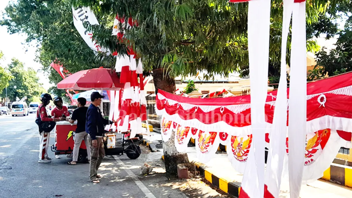 MENUNGGU PEMBELI: Riyawan, 53, warga asal Kota Bandung, sibuk merapikan bendera, di pinggir Jalan Pantura, Kelurahan Patokan, Kacamatan/Kota Situbondo, Minggu (9/8). (HUMAIDI/JPRS)
