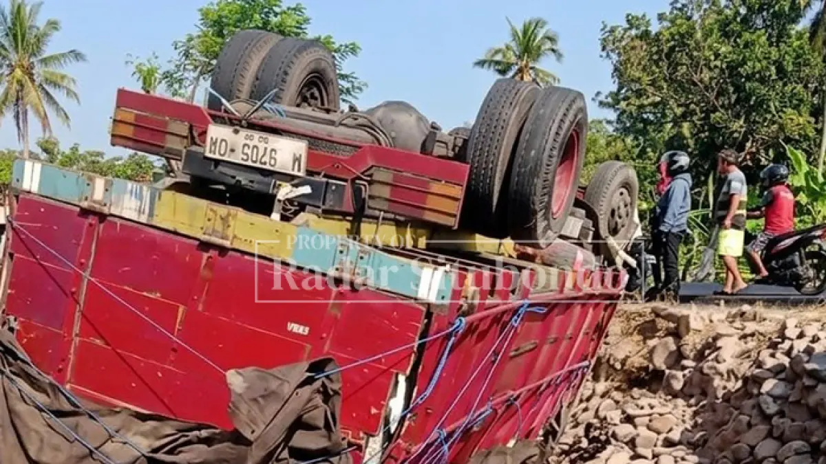 LAKA TUNGGAL: Sejumlah warga melihat truk terbalik di depan SMP Negeri Mlandingan, Kecamatan Mlandingan, Selasa (18/8). (HUMAIDI/JPRS)

