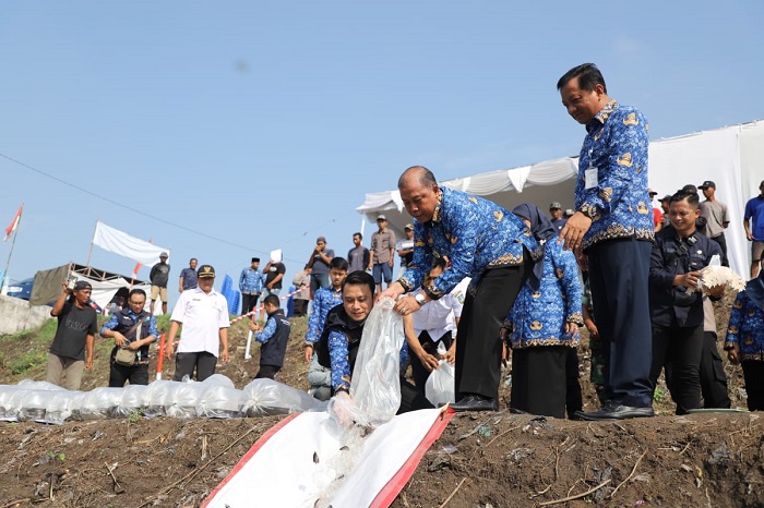 LESTARI: Pj Bupati Jombang, Sugiat, menebar bibit ikan di Sungai Ngotok Ring Kanal, Desa Bongkot, Kecamatan Peterongan, Rabu (29/11).