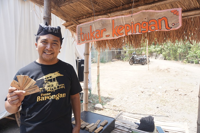 MENARIK: Kades Mojotrisno Nanang Sugiarto membawa kepingan bambu untuk alat pembayaran, satu keping bambu seharga Rp 2.000.