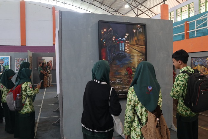 ANTUSIAS: Pengunjung menikmati karya lukis yang dipamerkan di Gor Merdeka Jombang, Rabu (6/12).