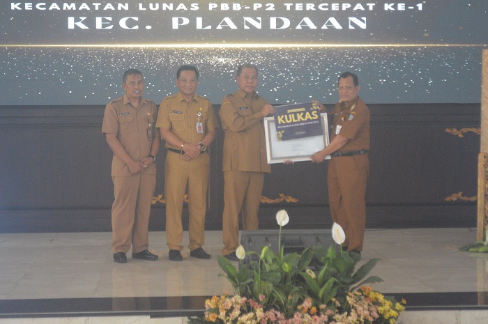 BERI REWARD: Pj Bupati Jombang Sugiat (dua dari kanan) memberi penghargaan Camat Plandaan Suparno (kanan) usai menyabet kecamatan lunas tercepat pertama Gebyar PBB-P2 di Pendopo Kabupaten Jombang.