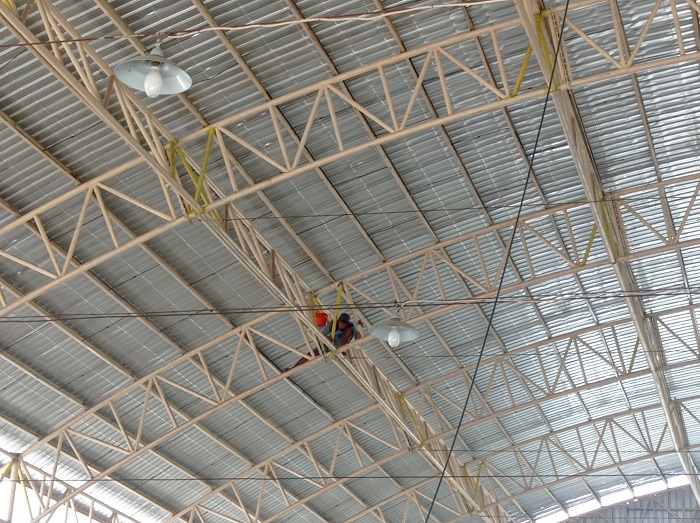 DIPERBAIKI: Salah satu pekerja tengah melakukan perbaikan bagian rangka atap Pasar Pon Jombang.