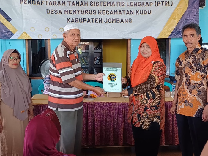 REALISASI: Kepala Desa Menturus Nyamiati (kerudung) menyerahkan sertifikat PTSL kepada warganya.