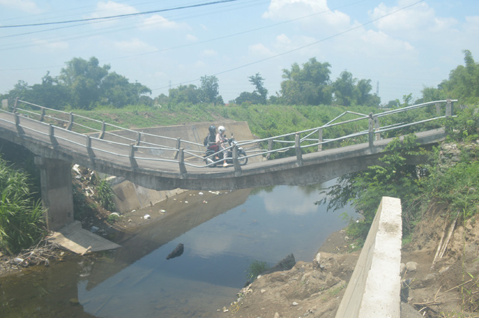 NEKAT: Warga melintas di jembatan Barongsawahan, Kecamatan Bandarkedungmulyo yang rusak, Sabtu (31/12).