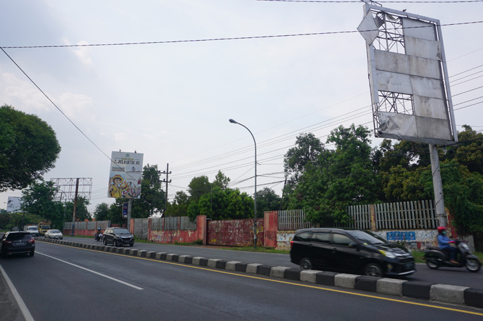MENGGELANTUNG: Material seng reklame bagian pojok atas di Kecamatan Peterongan nyaris terjatuh karena rusak, Jumat (29/12).