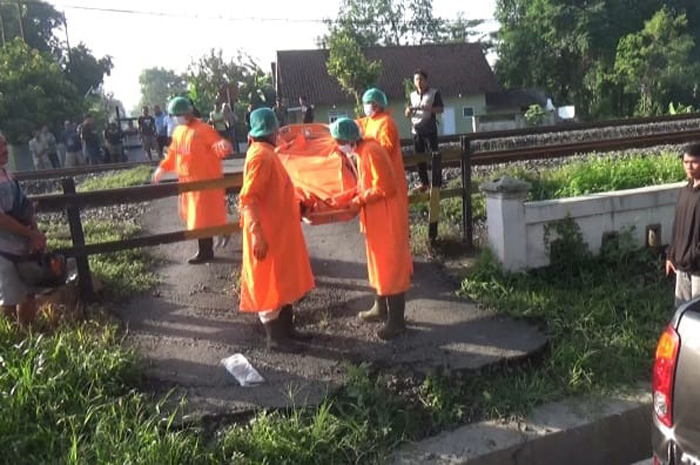 DIEVAKUASI: Petugas mengevakuasi korban yang tewas terambar kereta api di Jombang, Kamis (4/1).