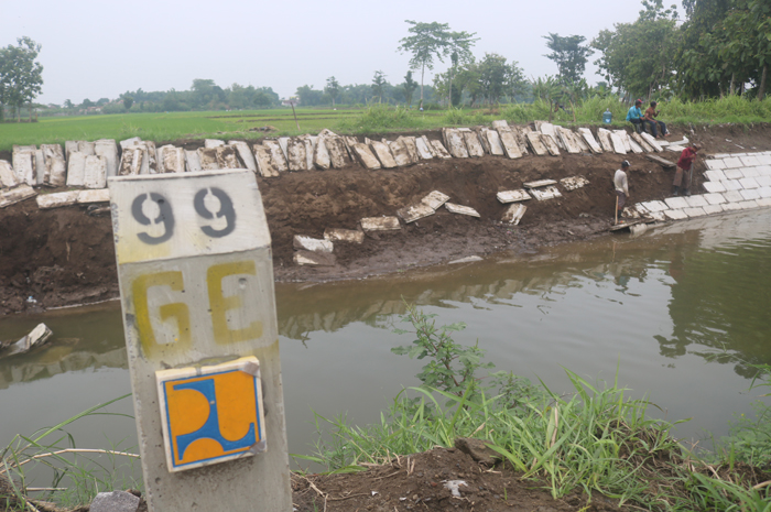 PORAK-PORANDA: Material precast lining proyek milik BBWS Brantas di Saluran Gude, Desa Tunggorono Kecamatan Jombang yang ambrol diangkat ke atas tanggul, Sabtu (7/1).