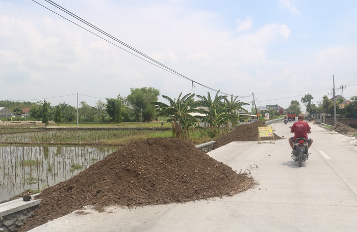 Kondisi jalan cor ruas Kabuh-Tapen dipenuhi tanah uruk.