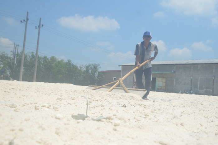 DIKERINGKAN: Khanafi tengah menjemur limbah ampas parutan kelapa di bekas pengeringan padi Desa Podoroto, Kecamatan Kesamben, Rabu (10/1).