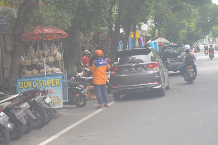 BEBAS KARCIS: Petugas jukir dari Dishub Jombang tengah memarkir kendaraan di kawasan parkir berlangganan Jalan A Yani, Selasa (23/1).