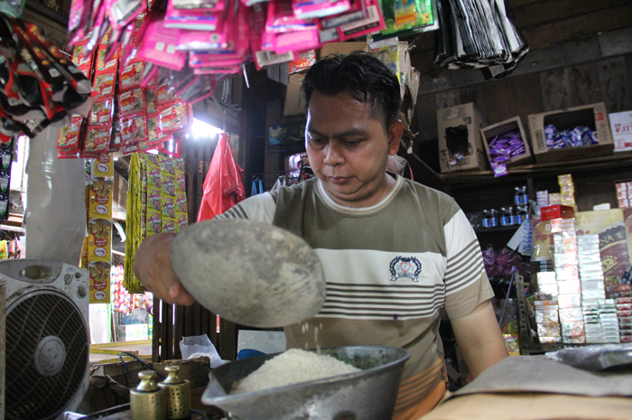 NAIK LAGI: Iwan Pujianto penjual beras di Pasar Pon Jombang saat melayani pembeli, Kamis (25/1).
