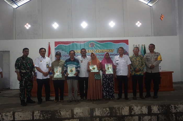 REALISASI: Kepala Desa Tunggorono Didik Dwi Mulyawan menyerahkan sertifikat PTSL kepada para warganya di gedung serbaguna.