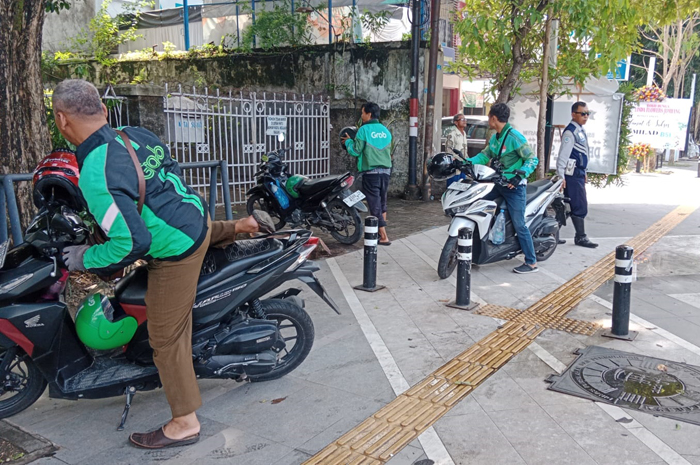 DITERTIBKAN: Petugas Dishub Jombang saat merazia kendaran parkir di trotoar Jl KH Wahid Hasyim, Kamis (1/2).