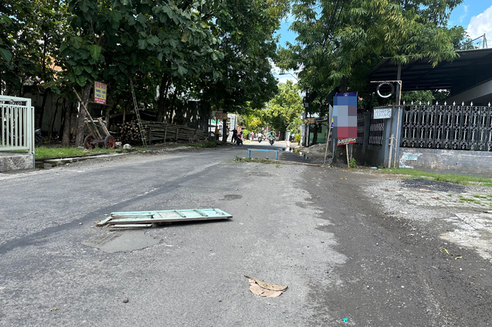 Warga memasang tanda pada jalan rusak yang baru saja diperbaiki menggunakan dana pribadi.