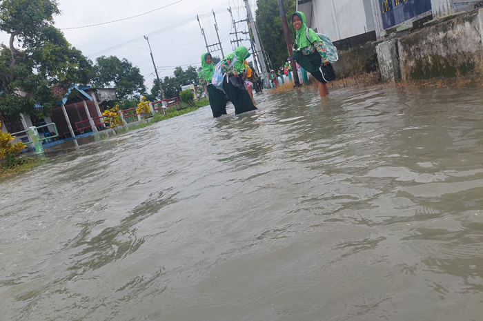 TERENDAM: Sejumlah siswa usai pulang sekolah melintas di jalan Desa Gedongombo, Kecamatan Ploso yang terendam banjir imbas luapan Kali Marmoyo, Rabu (7/2).