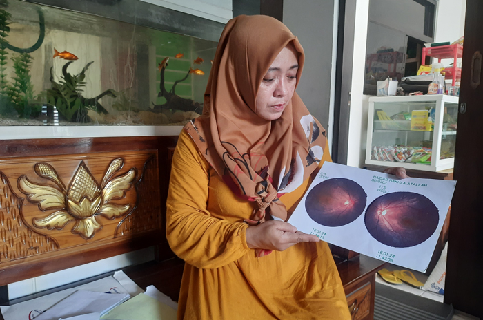 Erna menunjukkan hasil pemeriksaan mata anaknya yang rusak akibat terlempar kayu di sekolah.