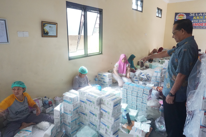 PEMBERDAYAAN MASYARAKAT: Kepala Desa Karangwinongan Iknan (berdiri) saat melihat proses pemasangan tali dan pengemasan masker di ruang BUMDes Lentera Jaya.
