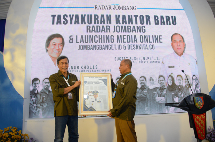 REDAKTUR KEHORMATAN: Pj Bupati Jombang Sugiat menerima cenderamata dari Direktur Jawa Pos Radar Jombang M. Nur Kholis, dalam tasyakuran kantor baru dan launching dua media online, Senin (4/3).