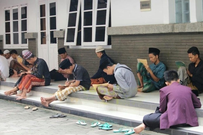MAKNANI: Santri memberi makna kitab kala ngaji di emper ndalem pengasuh Pondok Pesantren Tebuireng, Jombang.