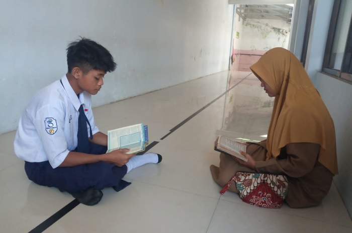 FOKUS: Anisa, pembimbing mulok keagamaan SMPN 3 Jombang saat menyimak siswanya mengaji.