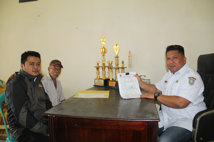 DEKAT: Kepala Desa Menganto Yunus Ardiyansyah (kanan) melayani warga yang mengambil SPTT PBB-P2 di Balai Desa Menganto, Mojowarno, Jombang.