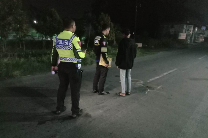 Petugas kepolisian melakukan olah tempat kejadian pemotor yang tewas terlindas truk gandeng di jalan nasional Jombang.