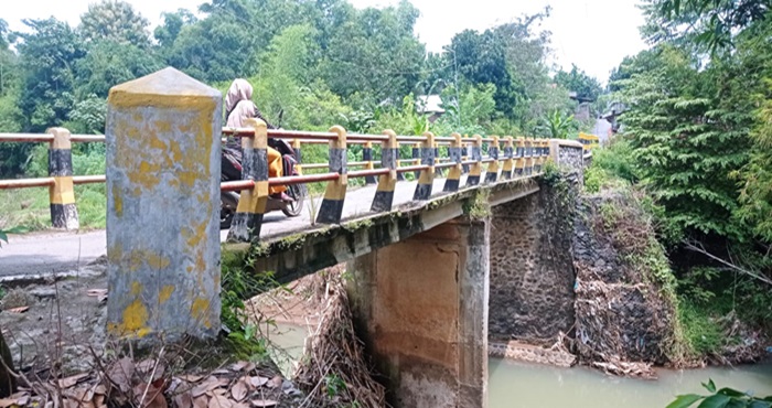BAKAL DITANGANI: Warga melintas di jembatan Desa Banjaragung, Kecamatan Bareng, Jombang terdampak banjir bandang 2021 akan diperbaiki pemerintah pusat.