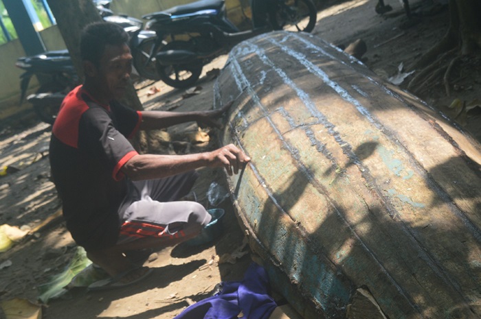 DIPERBAIKI: Samiran salah seorang pencari ikan Sungai Brantas tengah memperbaiki perahu yang rusak di Desa Sudimoro, Kecamatan Megaluh, Jombang.