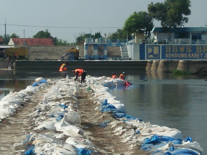 SEPARO TERPASANG: Pekerja tengah memasang jumbo bag untuk pembangunan kisdam di pintu enam Dam Karet Jatimlerek Jombang yang jebol.