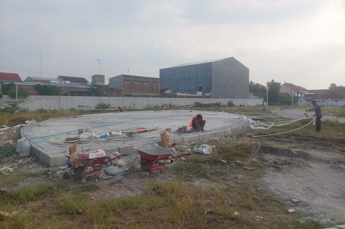 DIKERJAKAN: Pekerja tengah menyelesaikan pengerjaan landasan taman bermain atau playground di lokasi sentra PKL Jl KH Ahmad Dahlan yang gagal selesai dibangun 2023.